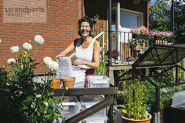 Glückliche Frau mit Plastikbehälter auf der Terrasse