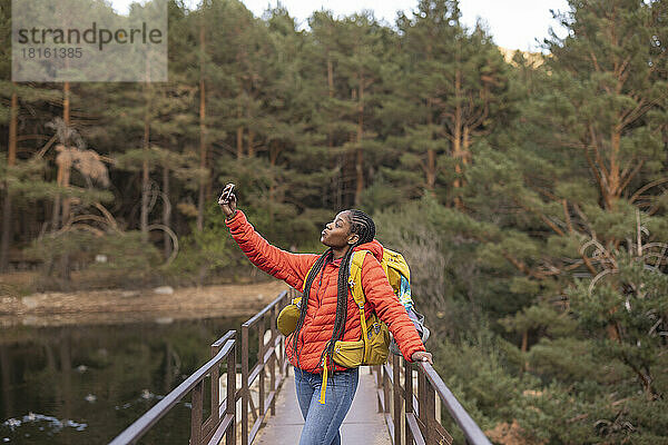 Junge Frau macht ein Selfie mit ihrem Mobiltelefon auf einer Brücke