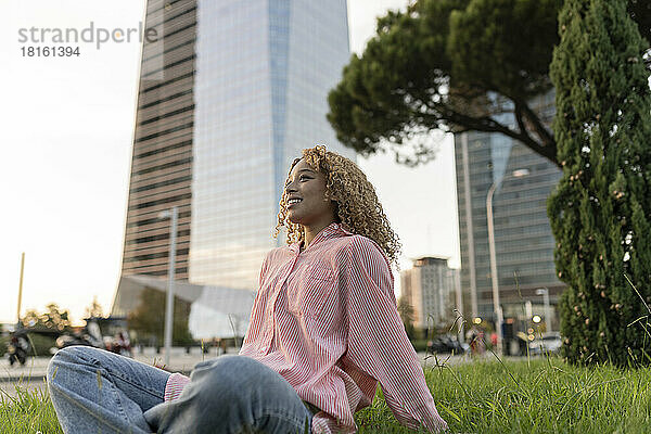 Lächelnde Frau entspannt sich im Gras in der Stadt