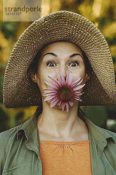 Reife Frau trägt Blume im Mund