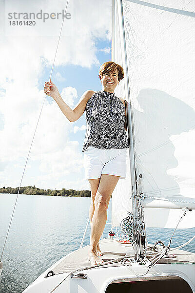 Lächelnde ältere Frau verbringt ihren Urlaub auf einem Segelboot