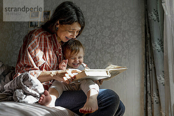 Glückliche Mutter mit Baby  die zu Hause ein Buch liest