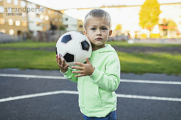 Netter Junge mit Fußball im Sportplatz