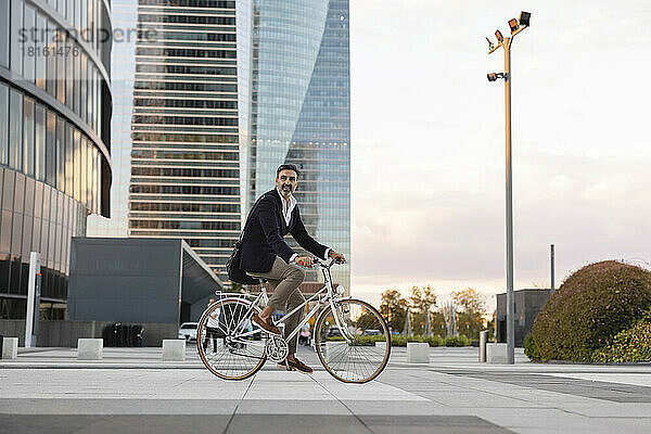 Reifer Pendler fährt bei Sonnenuntergang Fahrrad vor Bürogebäude