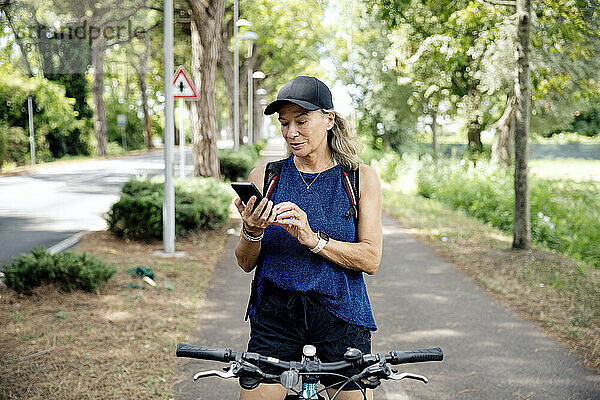 Ältere Frau benutzt Smartphone auf Fahrrad