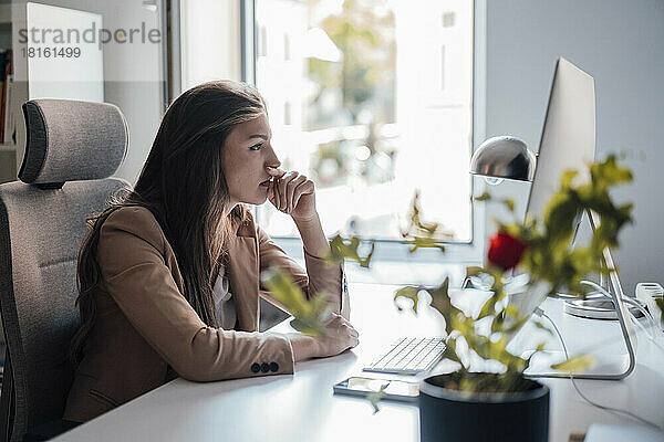 Geschäftsfrau blickt im Heimbüro auf den Desktop