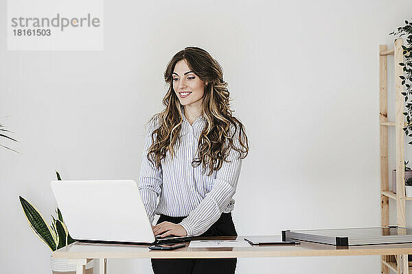 Junge Geschäftsfrau arbeitet im modernen Büro mit Laptop
