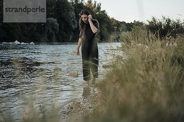 Junge Frau mit Haaren im Haar  die im Seewasser spaziert