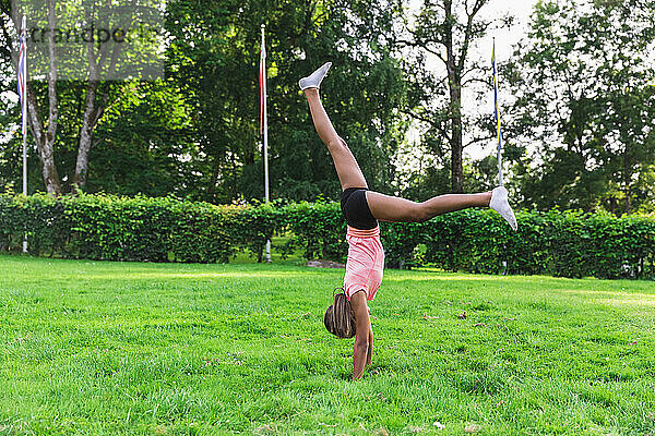 Mädchen übt Akrobatik auf Gras im Rasen
