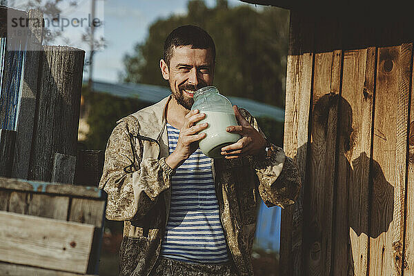Glücklicher reifer Mann  der an einem sonnigen Tag frische Milch aus einem Glas genießt