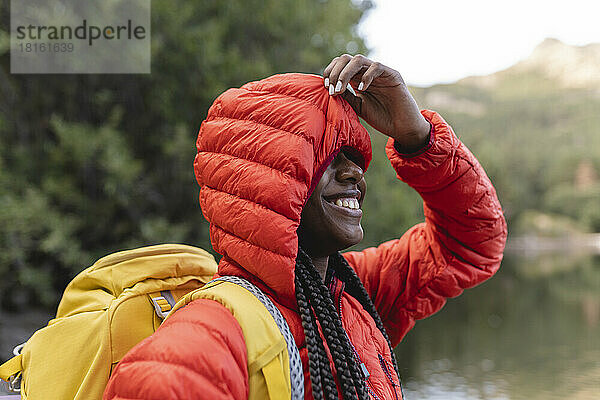 Lächelnde Frau bedeckt ihr Gesicht mit der Kapuze ihrer Jacke