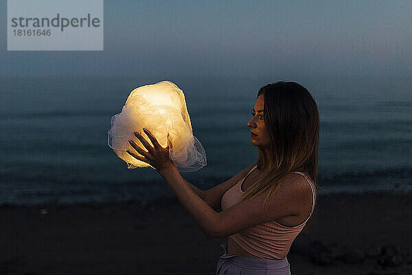 Frau hält Stoffball mit Licht  das den Mond in der Nacht simuliert