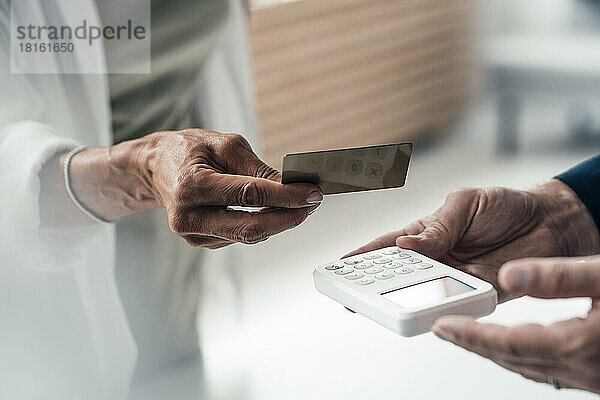 Hand einer Frau  die per Kreditkarte bezahlt