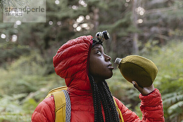 Durstige junge Frau mit Wasserflasche im Wald