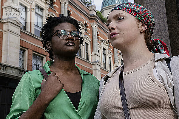 Junge Frau mit Freundin trägt Kopftuch vor Gebäude