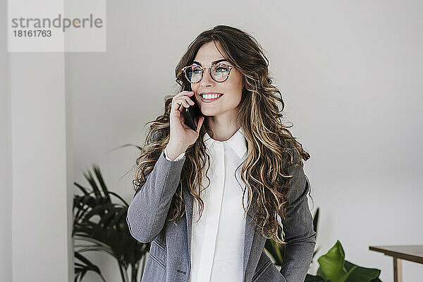 Lächelnde Geschäftsfrau benutzt Mobiltelefon im Büro