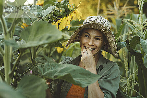 Lächelnde reife Frau isst Sonnenblumenkerne im Garten