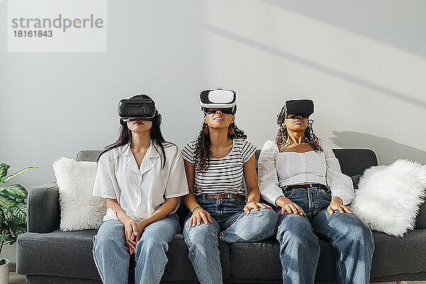 Junge Mitbewohner schauen zu Hause durch eine VR-Brille zu
