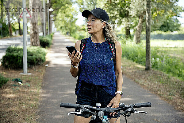 Ältere Frau hält Mobiltelefon auf Fahrrad