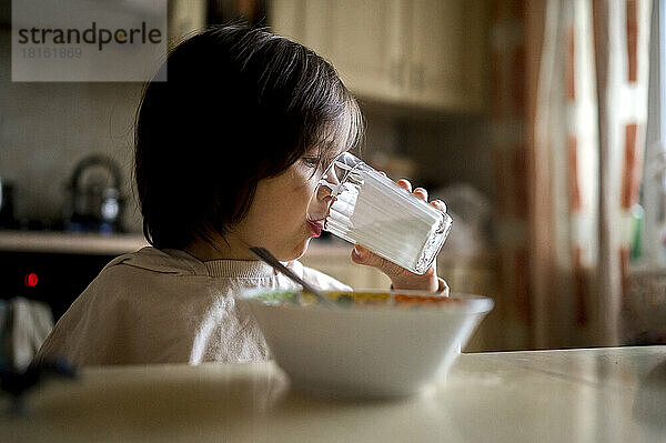Junge trinkt zu Hause Milch aus Glas