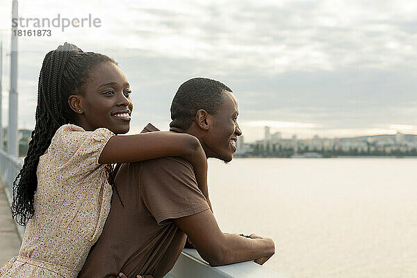 Nachdenkliche junge Frau steht mit ihrem Freund auf der Brücke