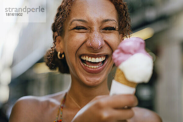 Fröhliche junge Frau  die Spaß mit Eis in der Hand hat
