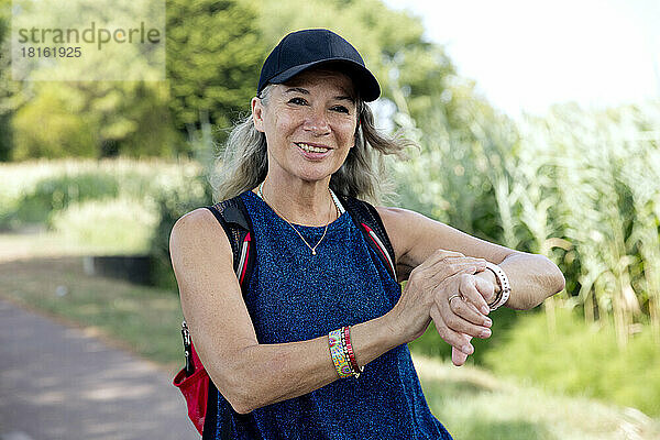 Lächelnde Frau überprüft Fitness-Tracker