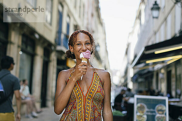 Lächelnde junge Frau leckt Eis
