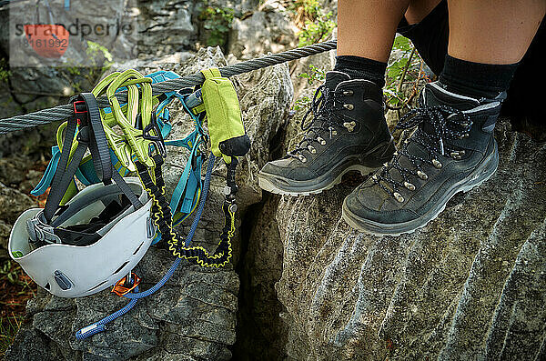 Legs of woman wearing hiking boots by climbing equipment rock