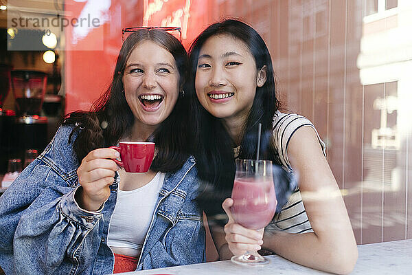 Gemischtrassiges lesbisches Paar genießt Getränke im Café