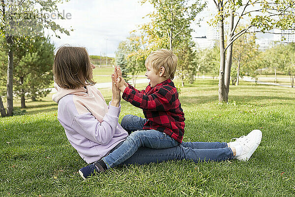 Mutter und Sohn spielen Klatschspiel im Park