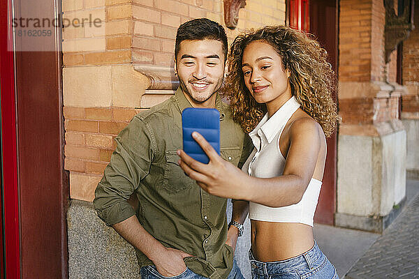 Lächelnde  gemischtrassige Freunde  die ein Selfie mit dem Handy machen