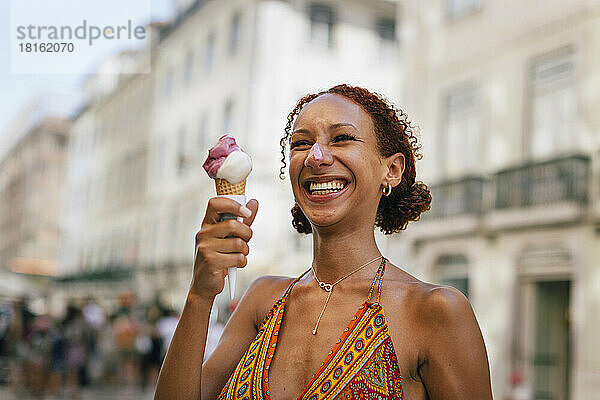 Fröhliche junge Frau mit lockigem Haar  die Eis genießt