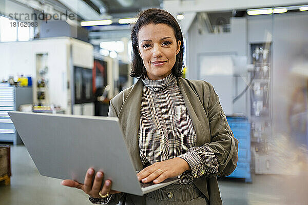 Lächelnde Geschäftsfrau mit Laptop in der Industrie
