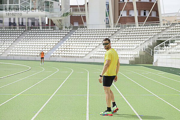 Mann mit Sonnenbrille steht auf Sportplatz