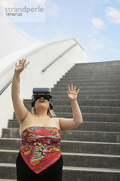 Junge Frau trägt Virtual-Reality-Simulator vor der Treppe