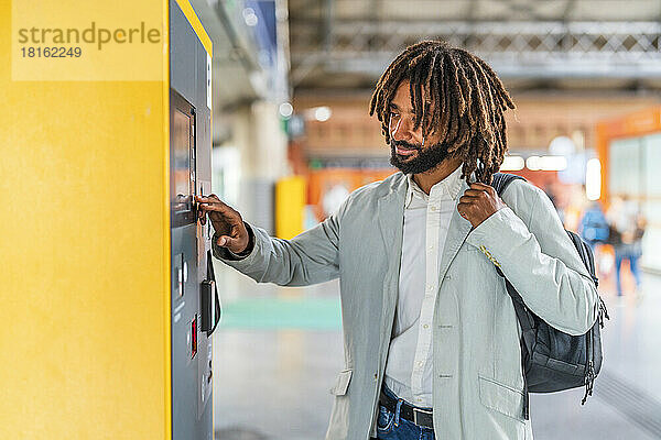 Lächelnder Geschäftsmann mit Touchscreen-Gerät am Bahnhof