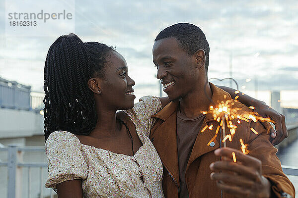 Couple with sparklers standing at sunset