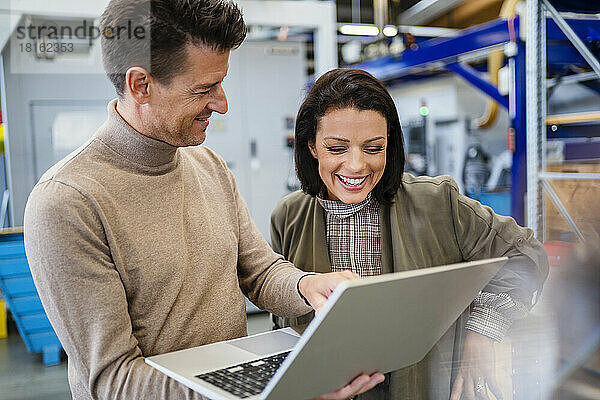 Lächelnder Geschäftsmann zeigt Geschäftsfrau in der Industrie Laptop