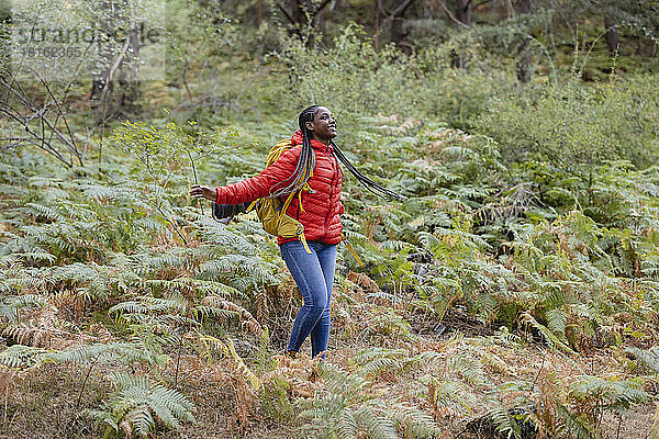 Cheerful young woman enjoying amidst plants in forest