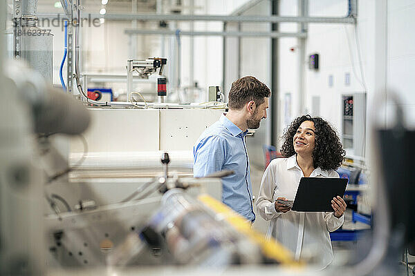 Glückliche Geschäftsfrau im Gespräch mit Kollegen in der Industrie