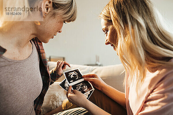 Frau diskutiert zu Hause über Ultraschall mit schwangerer Schwester