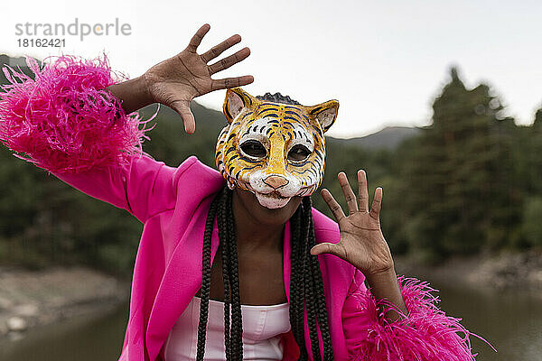 Junge Frau gestikuliert und trägt Tigermaske