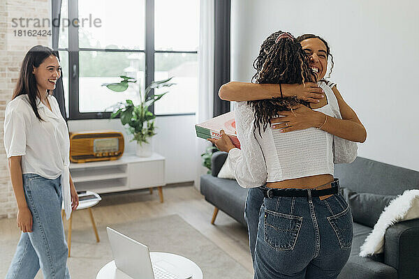 Fröhliche Frauen umarmen sich im heimischen Wohnzimmer