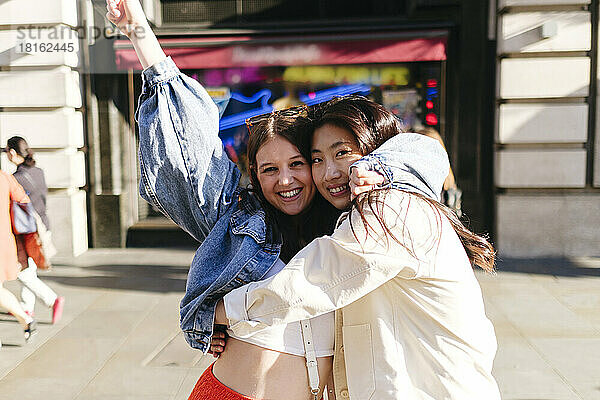 Fröhliche lesbische Frauen umarmen sich an einem sonnigen Tag auf der Straße