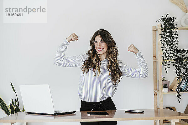 Starke Geschäftsfrau lässt im Büro Muskeln spielen