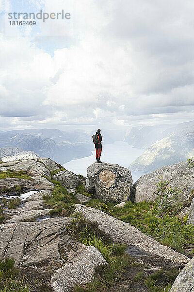 Wanderer blickt auf Berge  die auf Felsen stehen