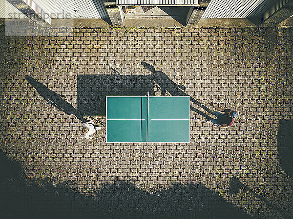 Mann mit Tochter spielt Tischtennis im Hinterhof