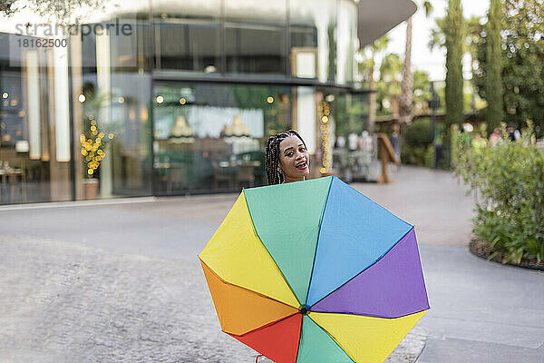 Frau hält bunten Regenschirm auf Fußweg