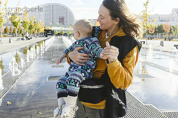 Mutter spielt mit Sohn im Stadtpark an Springbrunnen